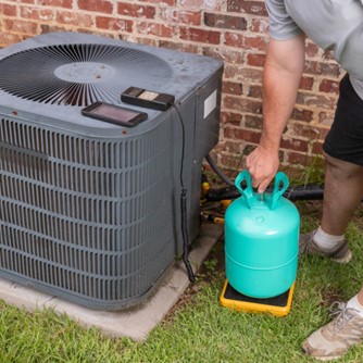 man adding refrigerant to AC